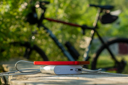 Power bank charges a smartphone in the forest on the background of a bicycleの写真素材