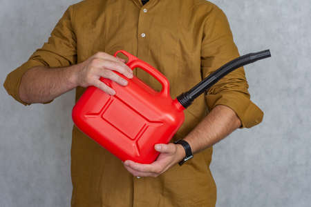 Man holds a red plastic gas canister in his handsの写真素材