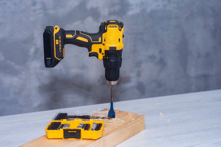 Electric cordless screwdriver on the battery on the table with a self-tapping screw in the boardの写真素材