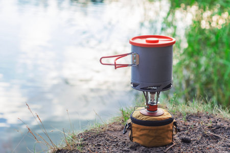 Summer camping in the open air, against the background of the lake. Tourist gas burner with pans for cookingの写真素材