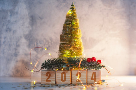 New Year holiday background. Inscription on wooden cubes of the number 2024. Banner with a New Year tree and bright glowing lightsの写真素材
