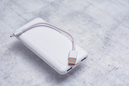 White power bank on a marble table. Portable charger for gadgets
