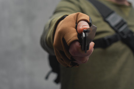 Male military man holding a tactical knife in his hand. Soldier with tactical backpack and brown glovesの写真素材