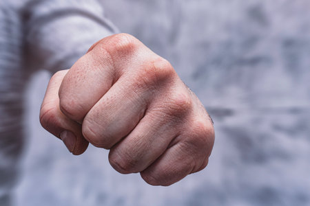 Close-up of a man in a shirt, doing a fist bump against a concrete wall.の写真素材