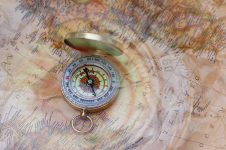 Antique brass compass resting on a world map, symbolizing travel and adventure
