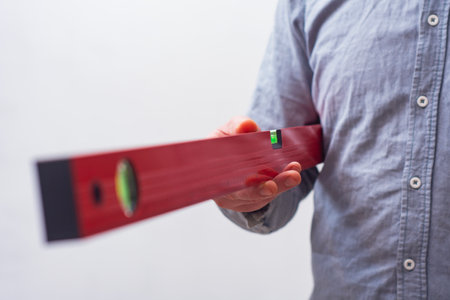 Close-up of a hand holding a red construction level. Tool for DIY, repair, and accuracy