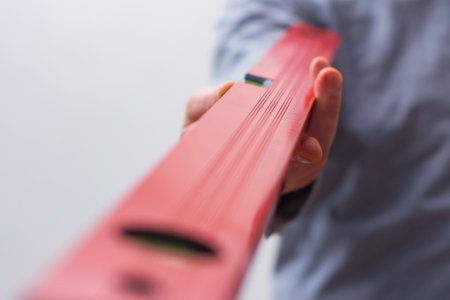 Close-up of a hand holding a red construction level. Tool for DIY, repair, and accuracy