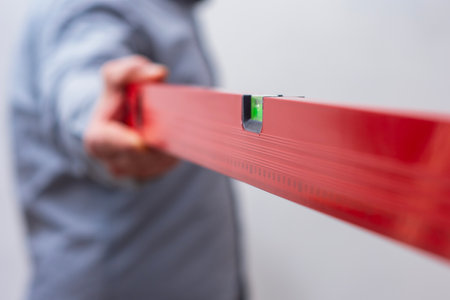 Close-up of a hand holding a red construction level. Tool for DIY, repair, and accuracy
