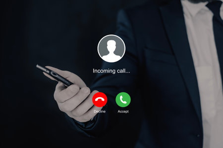 Notification of an incoming call on a smartphone in the hand of a businessman in a dark suitの写真素材