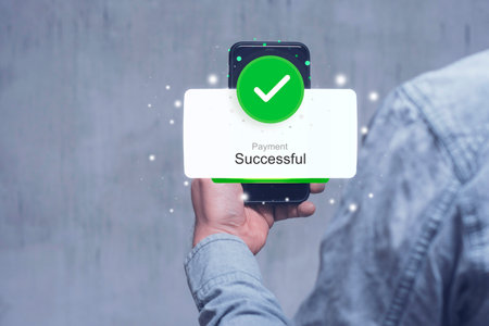 A Man in a denim sleeve holds a smartphone displaying a Payment Successful notification with a green...