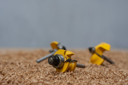 Yellow bits for router saw on a sawdust covered surface. Tools for woodworking and carpentry...