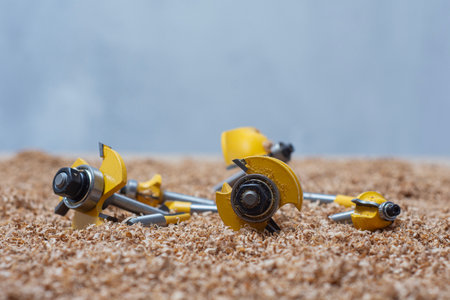Yellow bits for router saw on a sawdust covered surface. Tools for woodworking and carpentry...