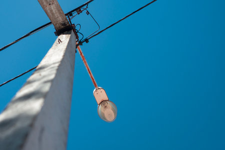 Street lamp stands tall with power lines stretching across a clear blue sky. Urban infrastructure in...