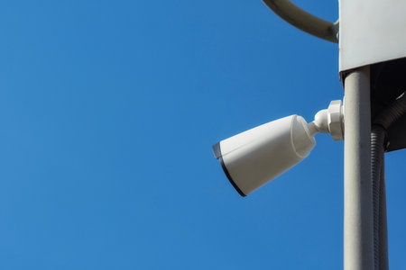 Outdoor CCTV camera on a metal pole against a clear blue sky