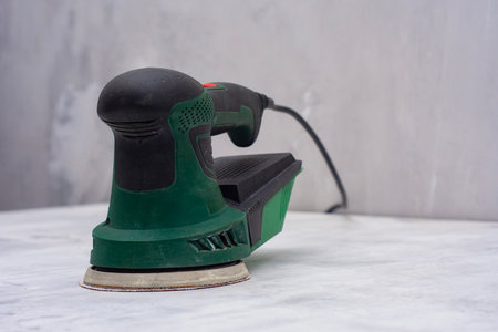 Closeup of green electric orbital sander on marble surface with sanding disk. Construction tool for renovationの写真素材