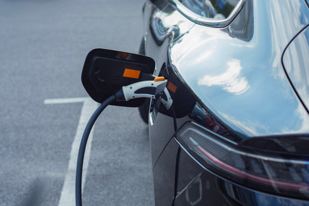 Electric car is connected to a charging station in a parking lot. Concept of an electric vehicle and energy source dedicated to the theme of sustainable mobility and clean energyの写真素材
