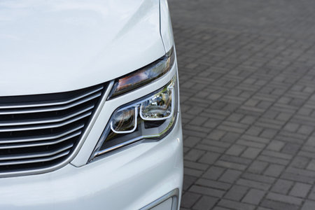 Front of a white van with modern headlights parked on an asphalt surface. Concept for automotive and commercial projectsの写真素材