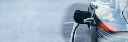 Electric car is connected to a charging station in a parking lot. Concept of an electric vehicle and energy source dedicated to the theme of sustainable mobility and clean energyの写真素材