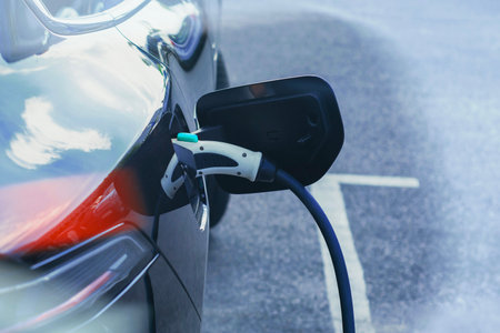 Electric car is connected to a charging station in a parking lot. Concept of an electric vehicle and energy source dedicated to the theme of sustainable mobility and clean energyの写真素材