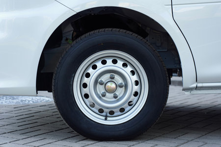 White van wheel with a steel rim, parked on a paved surfaceの写真素材