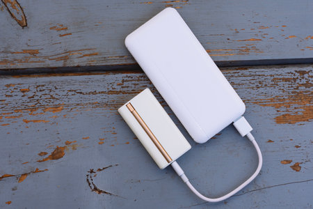Electronic device for heating tobacco is charged from a white pobank via USB cable. The topic of smoking, technology and bad habitsの写真素材