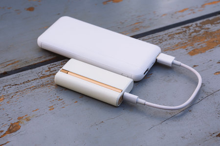 Electronic device for heating tobacco is charged from a white pobank via USB cable. The topic of smoking, technology and bad habitsの写真素材
