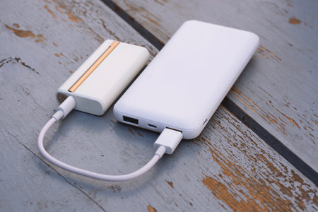 Electronic device for heating tobacco is charged from a white pobank via USB cable. The topic of smoking, technology and bad habitsの写真素材