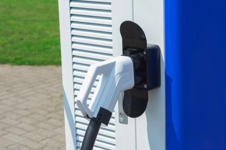Close-up electric vehicle charging connector plugged into a modern charging station. Concept clean energy, sustainable transportation, and the growing infrastructure for electric carsの写真素材