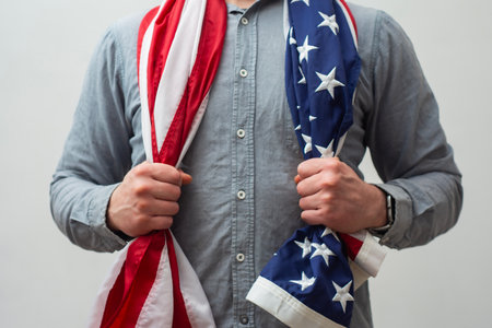 Close-up of a man holding the US flag with both hands. A symbol of pride and patriotism, freedom, unity and American valuesの写真素材