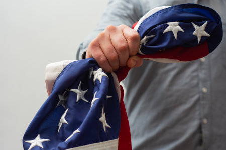 Close-up of a hand firmly clutching the flag of the United States symbolizes strength, resilience and unwavering patriotismの写真素材