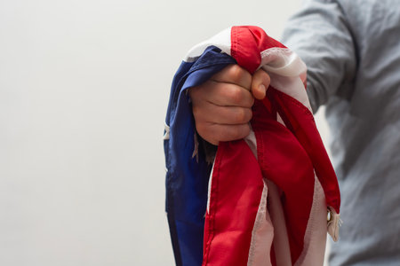 Close-up of a hand firmly clutching the flag of the United States symbolizes strength, resilience and unwavering patriotismの写真素材
