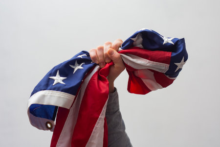 Close-up of a hand firmly clutching the flag of the United States symbolizes strength, resilience...