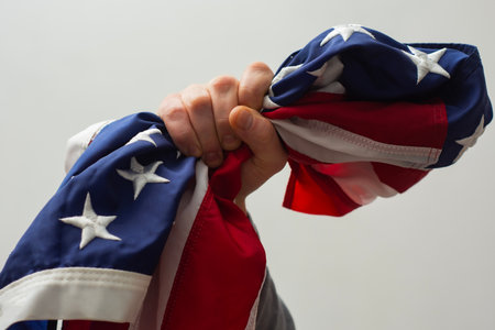 Close-up of a hand firmly clutching the flag of the United States symbolizes strength, resilience and unwavering patriotismの写真素材