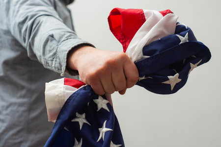 Close-up of a hand firmly clutching the flag of the United States symbolizes strength, resilience and unwavering patriotismの写真素材