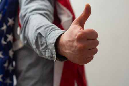 Close-up of a man making a thumbs up gesture with an American flag. Support and patriotic spiritの写真素材