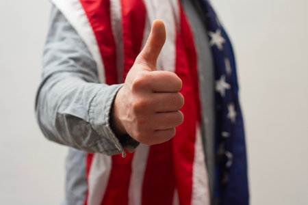 Close-up of a man making a thumbs up gesture with an American flag. Support and patriotic spiritの写真素材