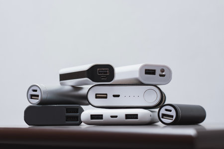 Stack portable power bank chargers of different shapes and sizes on a wooden table. Energy concept, mobile technology for charging electronic devicesの写真素材