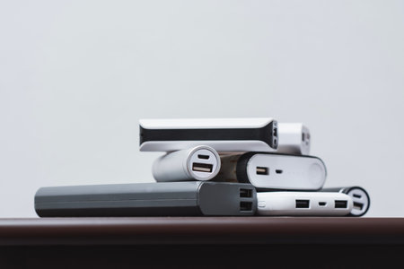 Stack portable power bank chargers of different shapes and sizes on a wooden table. Energy concept, mobile technology for charging electronic devicesの写真素材
