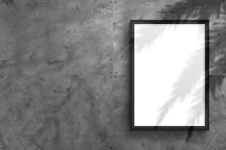 A blank vertical mockup of a framed poster hangs on a textured concrete wall in an industrial style to showcase the designの写真素材