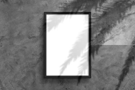 A blank vertical mockup of a framed poster hangs on a textured concrete wall in an industrial style to showcase the designの写真素材
