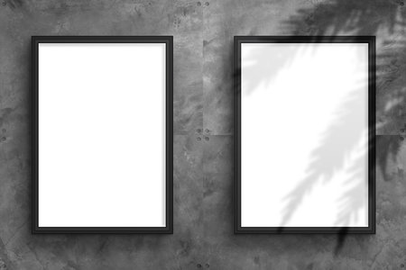 Two blank vertical mockup of a framed poster hangs on a textured concrete wall in an industrial style to showcase the designの写真素材