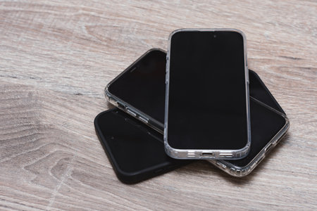 Stack of modern smartphones with a protective case on a wooden surface. Concept mobile technology...