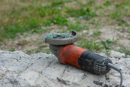 Close-up of an angle grinder with a green segmented diamond cutting disc placed on rough concrete paving stonesの写真素材