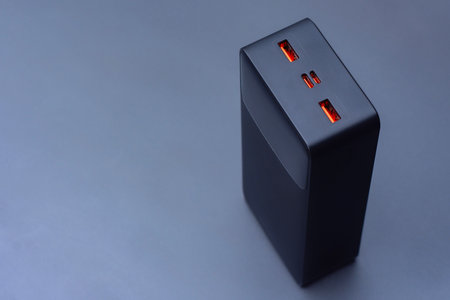Large portable Power Bank in black color on a soft light background. Power source for charging...