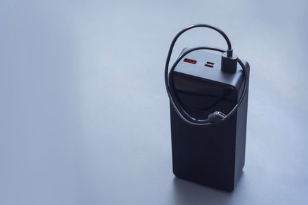Large portable Power Bank in black with USB-C charging cable on a soft light background. Power source for charging smartphones and devices on the goの写真素材