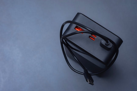 Large portable Power Bank in black with USB-C charging cable on a soft light background. Power source for charging smartphones and devices on the goの写真素材