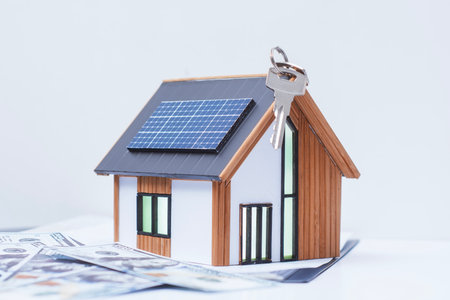 Miniature home with solar panels, keys and deeded dollars. Real estate deal concept, eco-friendly housing and green energy investmentの写真素材