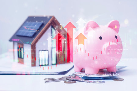 A pink piggy bank with US dollars and coins with a model of a house. Overlay of stock market data and arrows pointing upward. Concept of value growth on eco-friendly homes and loansの写真素材