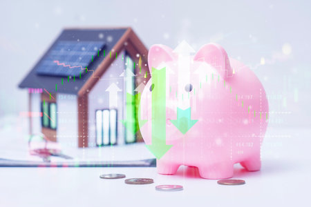A pink coin piggy bank with a model of a solar-powered house superimposed on stock market charts. Concept of fluctuating financial returns and risks for real estateの写真素材