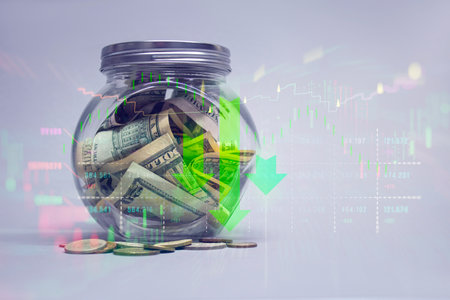 A glass jar with bills and coins, against a background of graphs with green arrows pointing downward. Concept decline in interest rates and potential decrease in incomeの写真素材